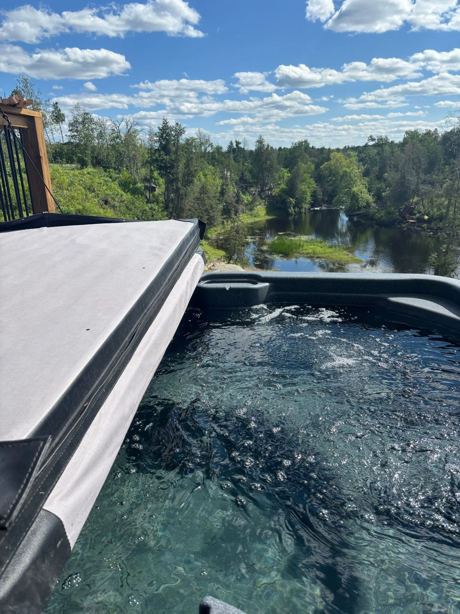 A cottage hot tub above the Skootamatta River at Bridgewater Resort, trees and rock along the far bank