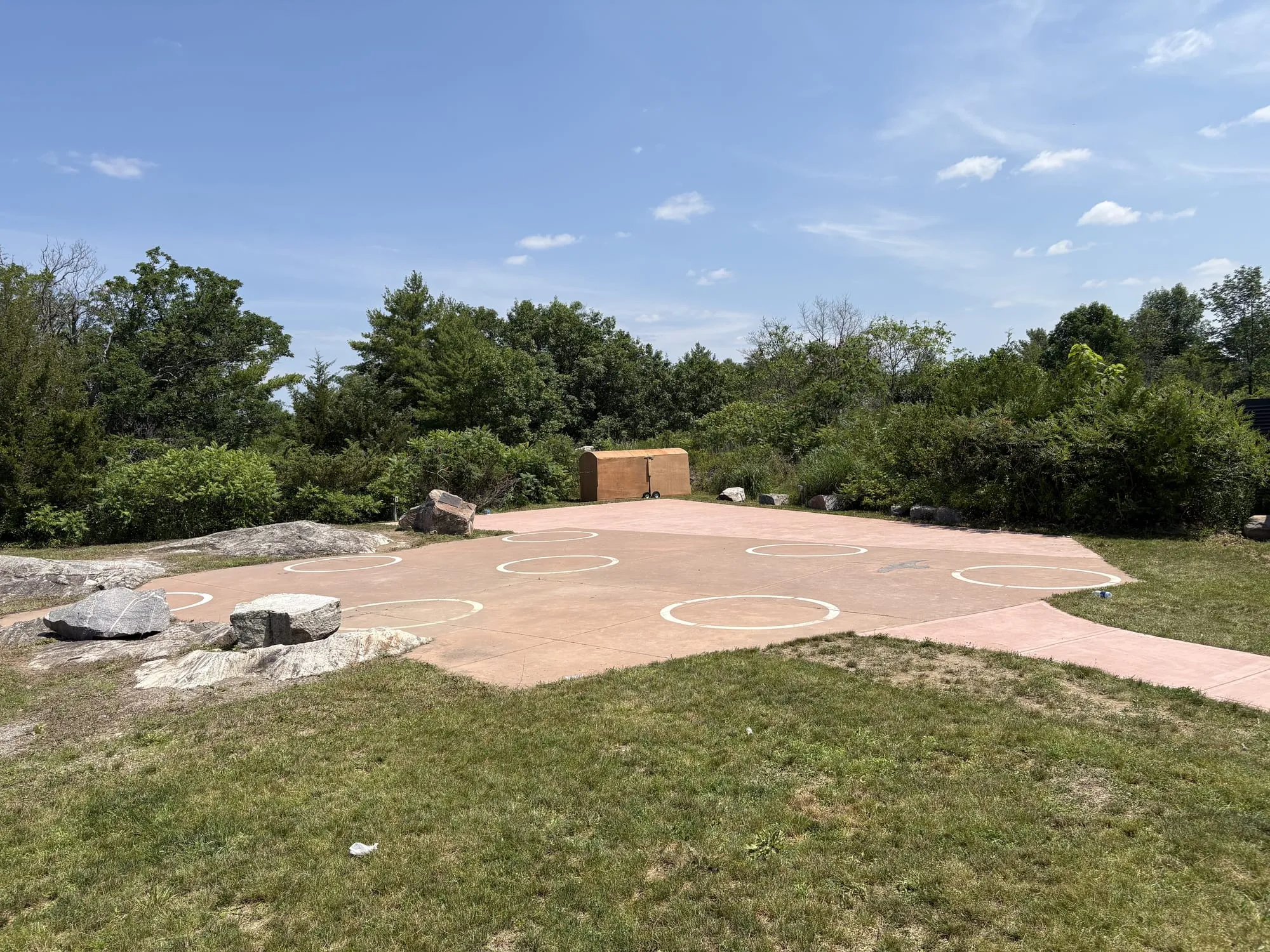 The concrete viewing pad at the L&A Dark Sky Viewing Area, circles marked on its surface, ringed by low trees