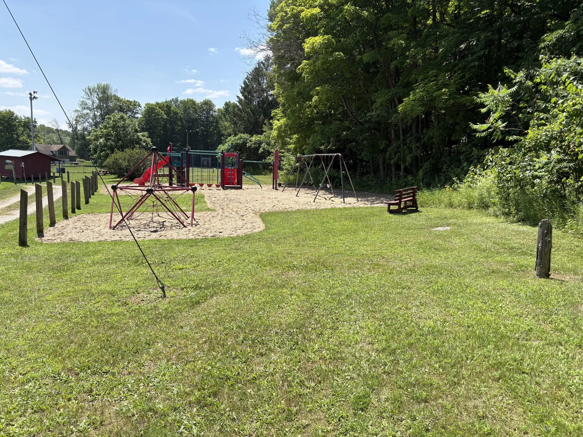 The playground at Kennebec Recreation Park in Arden, red slide and swings on a sand pad