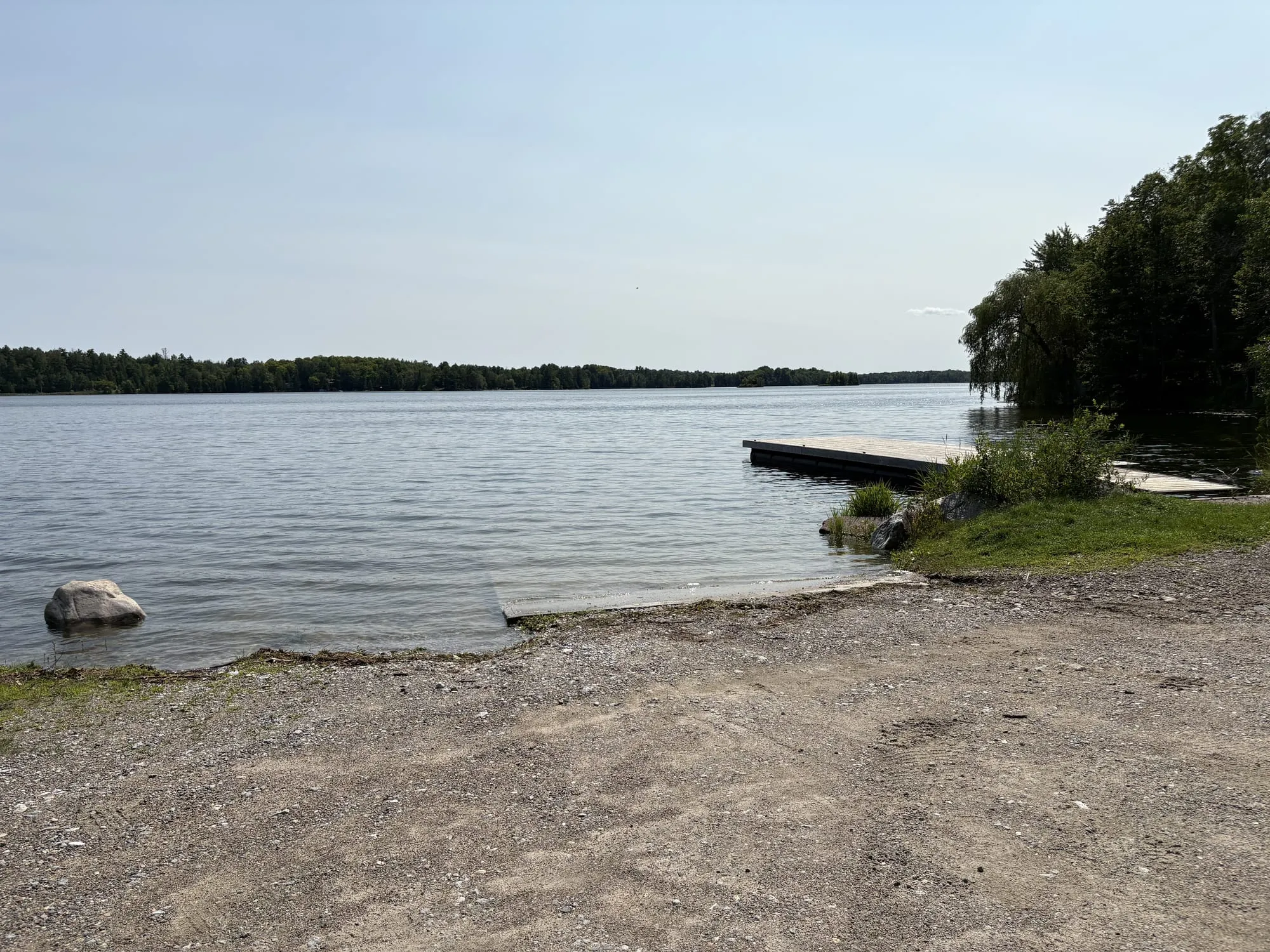 The concrete boat ramp and floating dock beside Long Lake Beach, the lake opening out to a wooded far shore